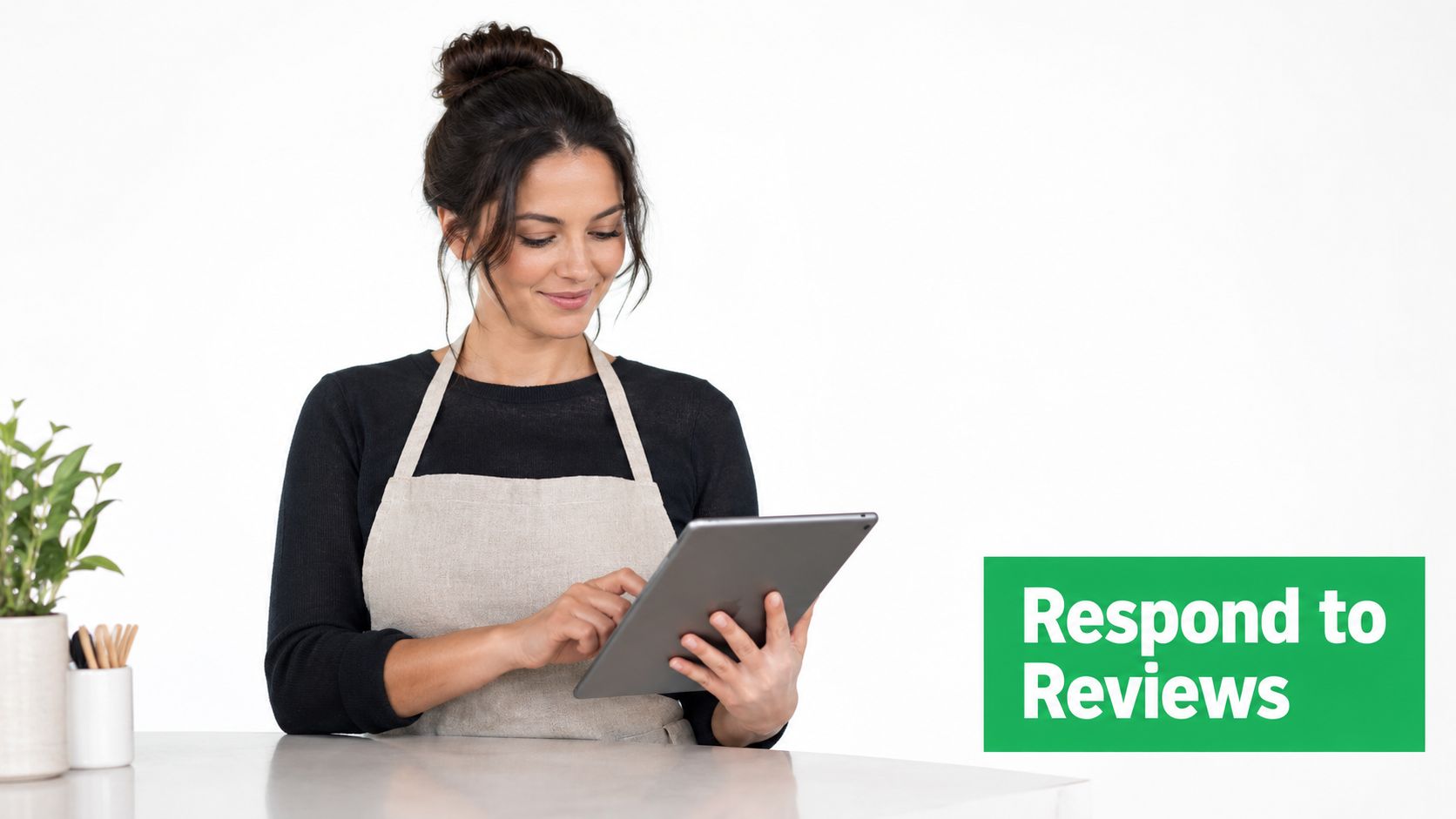 A female business owner wearing an apron uses a tablet to efficiently respond to customer online reviews.
